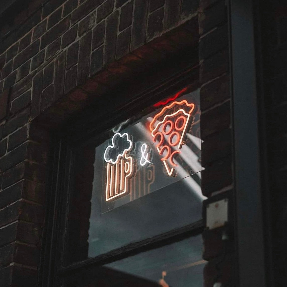 pizza and beer neon sign on a brick wall. pizza restaurant.