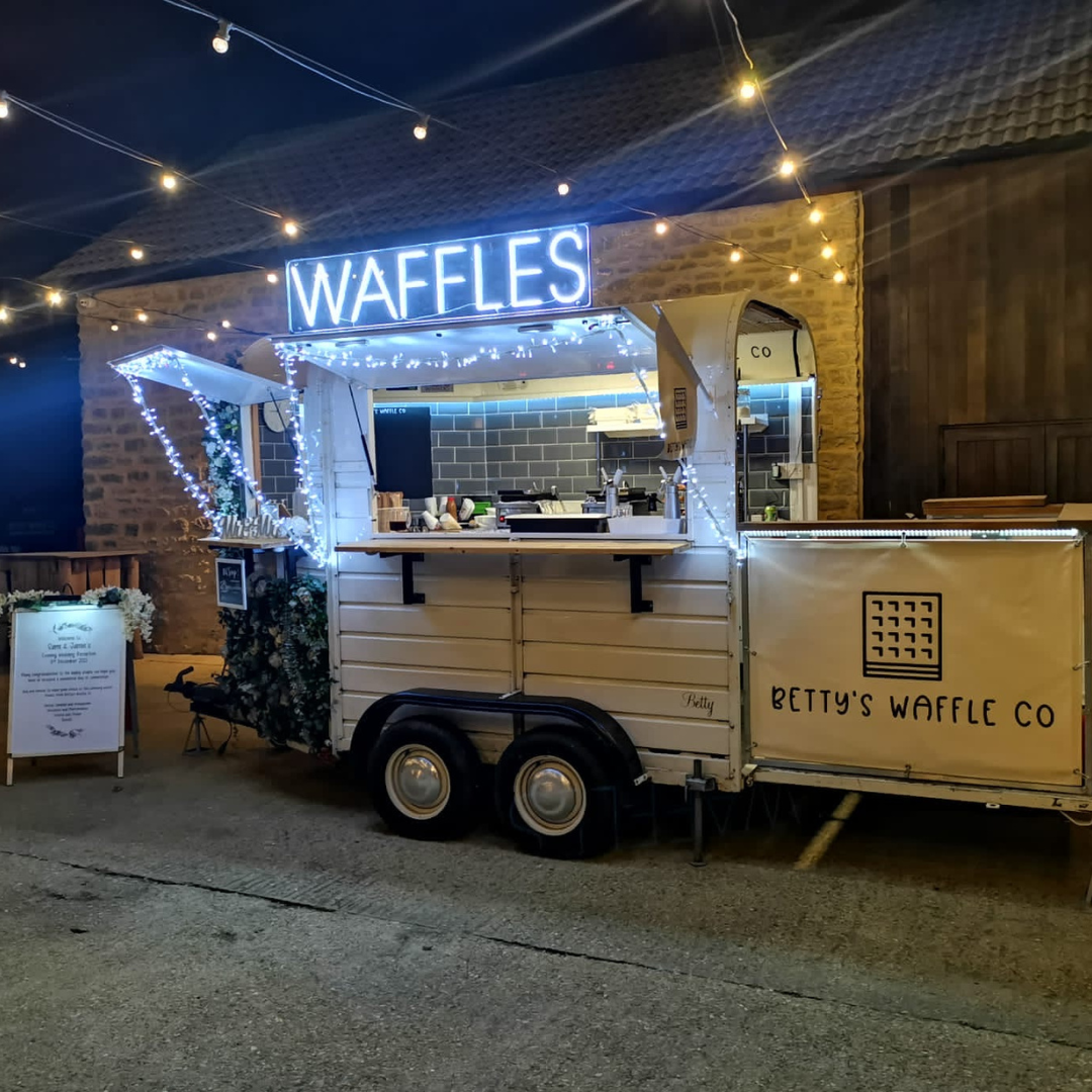 Glowing neon sign displaying the word 'Waffles' in white against a dark background. Perfect for waffle traders, dessert shops, and waffle shops