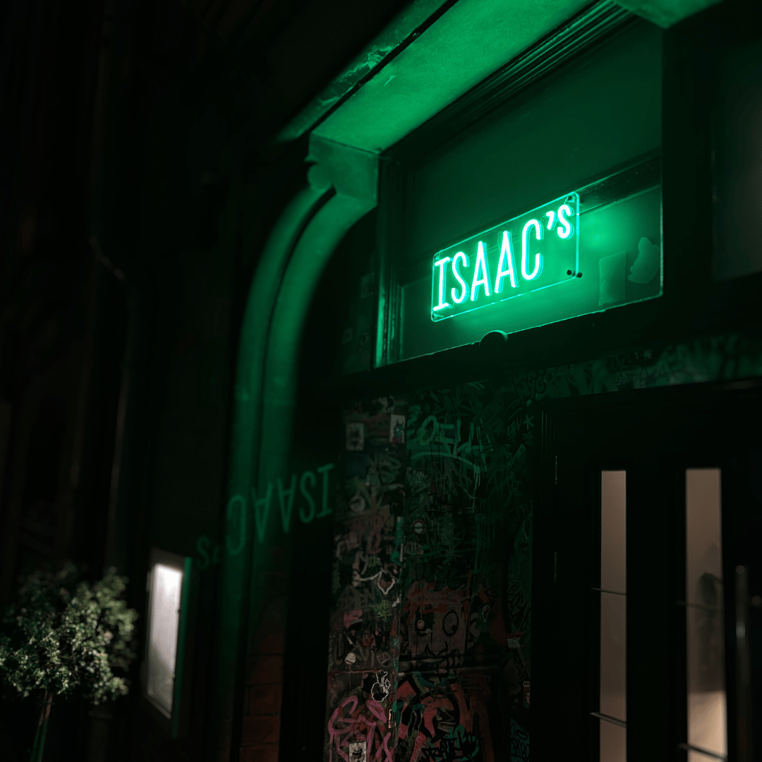 A NeonCow green neon sign saying "isaac's" for a Birmingham restaurant entrance, it is lighting up the doorway and inviting people in with the neon light. it is a modern decor with a instagrammable entrance.